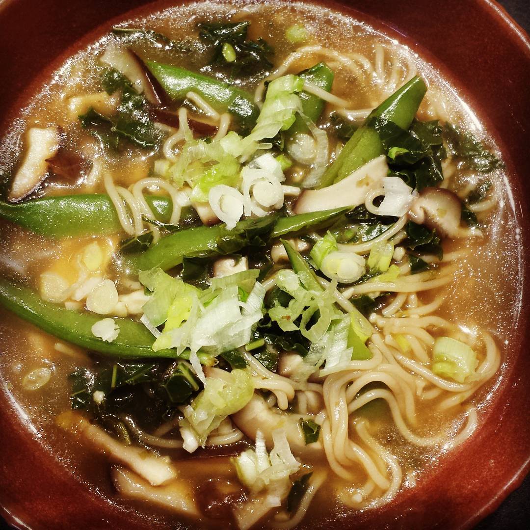 Bowl of homemade ramen, showing snow peas, noodles, green onions, broth, seaweed.